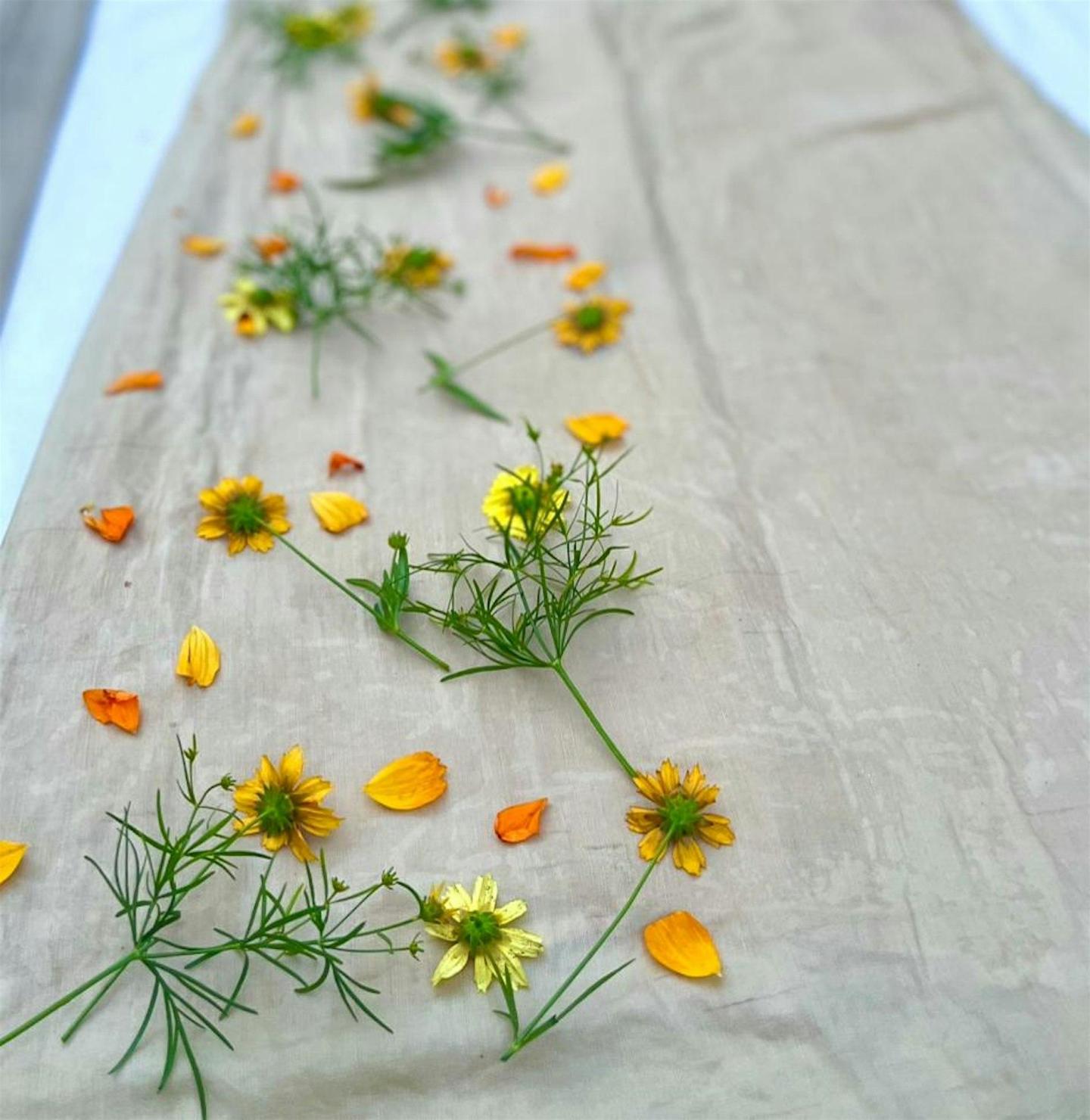 Yellow and orange flowers arranged on beige fabric.
