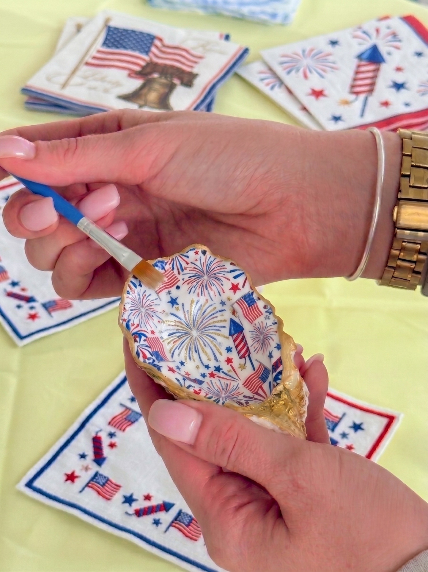 Decorative oyster shell with patriotic colors held by hands.